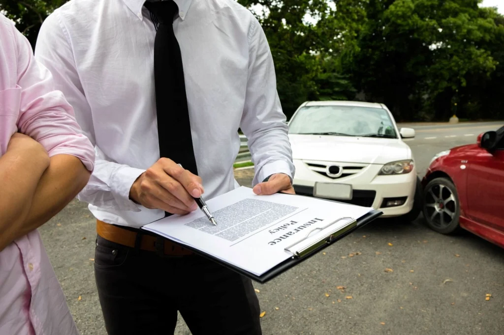 midsection-insurance-agent-discussing-agreement-with-client-while-standing-by-cars (1)